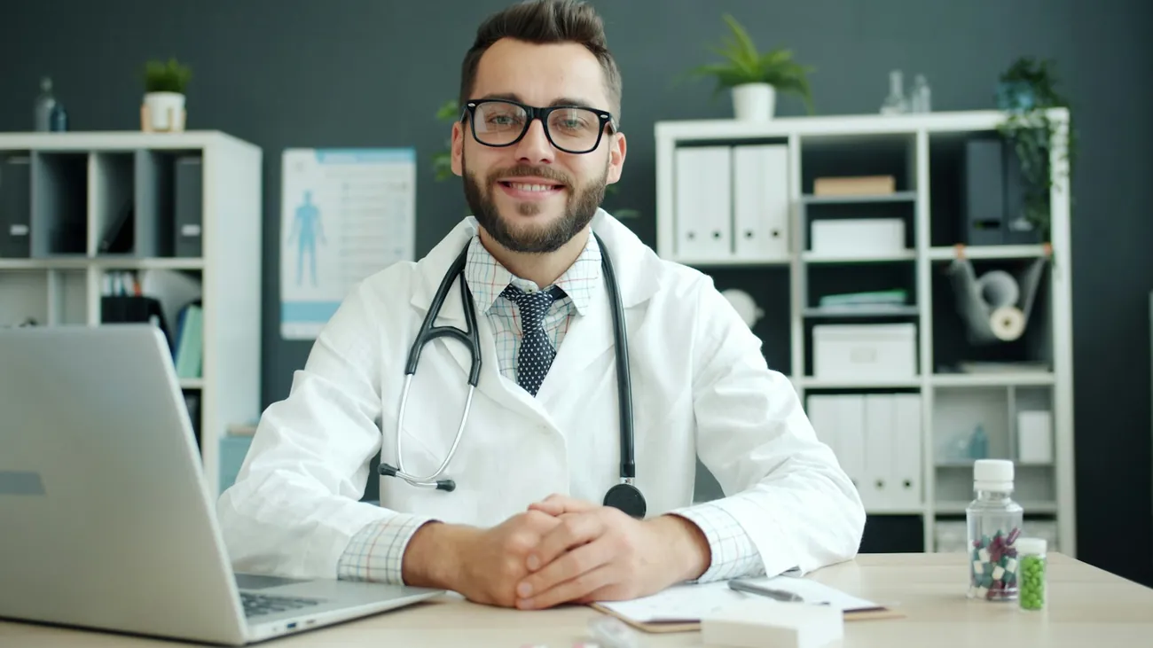 Médico sonriente en su consulta, con bata y estetoscopio